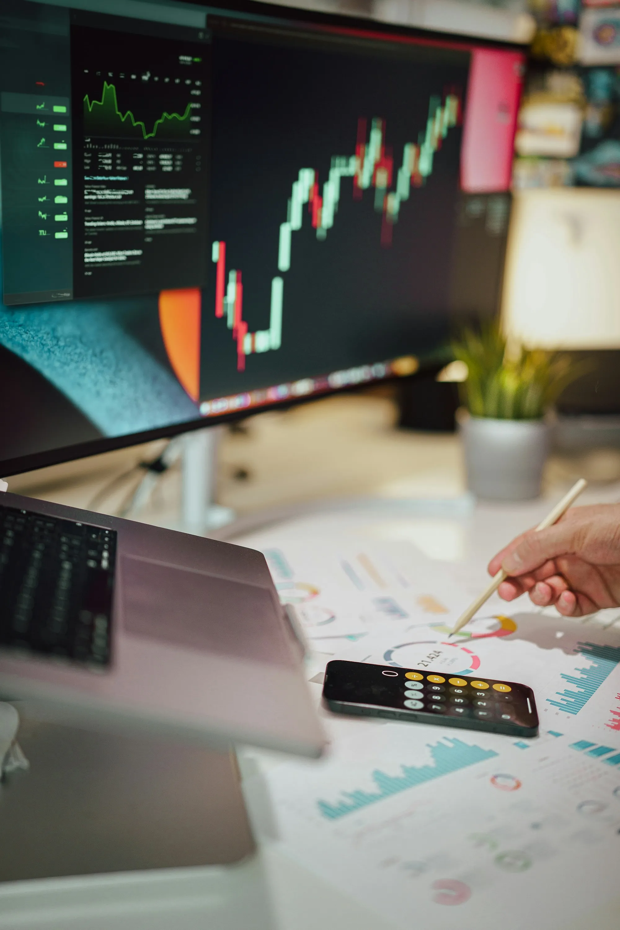 Un trader toma notas en papel junto a una pantalla que muestra un gráfico de precios
